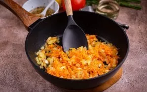 Į keptuvę įpilkite 3 šaukštus augalinio aliejaus ir sudėkite smulkintą svogūną bei morką. Kepkite ant silpnos ugnies, reguliariai maišyda...