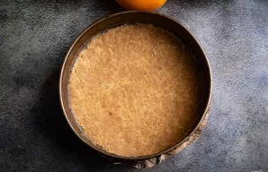 Sūrio pyrago formos dugną išklokite kepimo popieriumi. Sudėkite trupinių masę ir gerai suspauskite, suformuodami lygų sluoksnį. Formą pad...