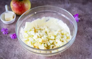 Įdėkite obuolių kubelius į varškės masę.