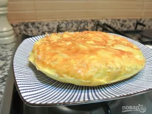 Staigiai apverskite omletą nuo lėkštės atgal į keptuvę, uždenkite dangčiu ir kepkite dar kelias minutes. Perkelkite jį atgal į lėkštę.