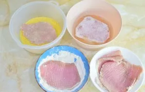 Kiekvieną mėsos gabalėlį apvoliokite miltuose, tada pamirkykite kiaušinio plakinyje ir apvoliokite džiūvėsėliuose.