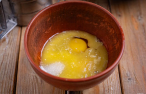 Į atskirą dubenį įmuškite kiaušinius, suberkite likusį cukrų, supilkite ištirpintą sviestą. Viską išmaišykite šluotele iki vientisos masės.