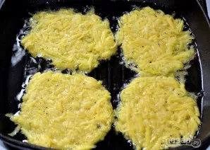 Šaukštu dėkite tarkius į keptuvę ir paskleiskite, kad blynai būtų ploni.