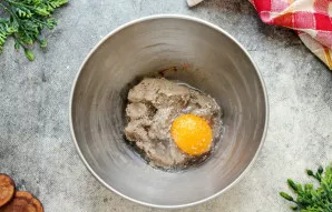 Į dubenį su kepenėlių mase įmuškite kiaušinį, pasūdykite ir pabarstykite pipirais.