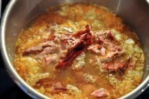Tada sudėkite troškintas daržoves ir susmulkintą šonkauliukų mėsą. Pagardinkite druska ir pipirais pagal skonį. Troškinkite dar 5 minutes.