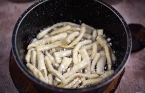 Puode storu dugnu ant vidutinės ugnies įkaitinkite augalinį aliejų ir porcijomis dėkite tešlos makaronus.