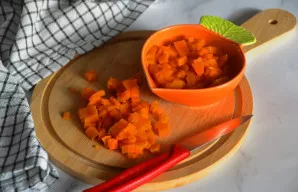 Supjaustykite morką smulkiais kubeliais.