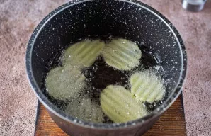 Tinkamame puode ant vidutinės ugnies gerai įkaitinkite augalinį aliejų ir porcijomis dėkite bulvių griežinėlius, kepkite juos iš visų pus...