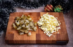 Raugintus agurkus taip pat supjaustykite mažais kubeliais. Kiaušinius nulupkite ir smulkiai supjaustykite.