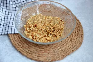 Graikinių riešutų branduolius stambiai sukapokite peiliu.