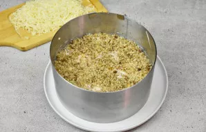 Ant majonezo sluoksnio plonai paskirstykite smulkintus graikinius riešutus ir smulkiai tarkuotą sūrį.