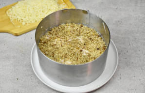 Ant majonezo plonu sluoksniu paskirstykite smulkintus graikinius riešutus ir smulkia tarka tarkuotą sūrį.