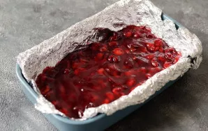 Kepimo indo dugną išklokite folija arba kepimo popieriumi. Ant dugno paskleiskite vyšnių įdarą.