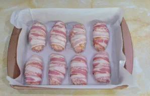 Iš mėsos masės suformuokite nedidelius kotletukus ir apvyniokite juos šonine. Suktinukus dėkite ant aliejumi pateptos skardos.