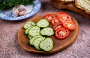 Agurkus supjaustykite plonais griežinėliais, pomidorus taip pat supjaustykite plonais griežinėliais.