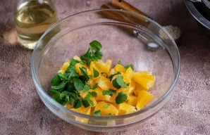 Į didelį dubenį sudėkite apelsino gabalėlius, pridėkite mėtos lapelius.