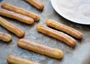 Pašaukite į iki 200 laipsnių įkaitintą orkaitę 15 minučių. Kol mūsų churros kepa, paimkite plačią lėkštę, supilkite į ją cukrų ir suberki...