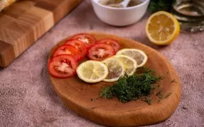 Plonai supjaustykite pusę citrinos ir pomidorą. Smulkiai supjaustykite šviežius krapus.