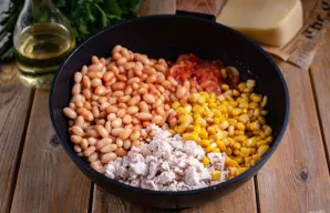 Į keptuvę prie kitų ingredientų sudėkite pupeles (be skysčio), kukurūzus (taip pat be skysčio) ir virtos vištienos gabalėlius.