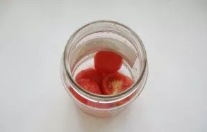 Paimkite 500 ml stiklainius ir sterilizuokite juos. Į stiklainio dugną įpilkite arbatinį šaukštelį acto. Tada sudėkite pomidorų sluoksnį.