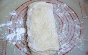 Išlyginkite tešlos lakštą ir sulankstykite vokeliu, pirmiausia susidurdami dvi priešingas puses.