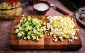 Nulupkite kietai virtus kiaušinius, smulkiai supjaustykite arba netgi sutarkuokite. Agurkus supjaustykite mažais kubeliais.