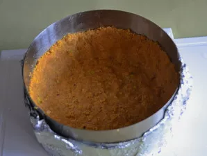 Į formos dugną sudėkite 1/3 trupinių ir gerai suspauskite ranka ar stiklinės dugnu. Iš likusių trupinių suformuokite 5–6 cm aukščio krašt...