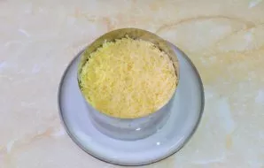 Viršutinis sluoksnis bus tarkuotas sūris. Tvirtai suspauskite visus salotų sluoksnius ir nuimkite serviravimo žiedą.