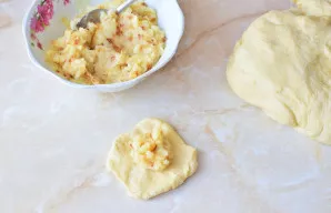 Iš paruoštos tešlos suformuokite nedidelę plokštelę, dėkite įdarą ir suformuokite pyragėlį.