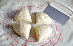 Gausiai pabarstykite miltais darbo paviršių ir padalinkite tešlą į 4 dalis.