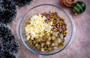 Pridėkite raugintų agurkų kubelius ir smulkintus kiaušinius.