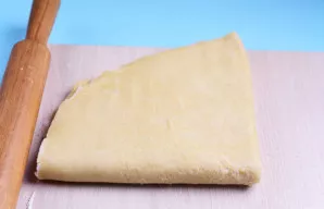 Dar kartą perlenkite tešlą pusiau ir šiek tiek perkočiokite kočėlu.